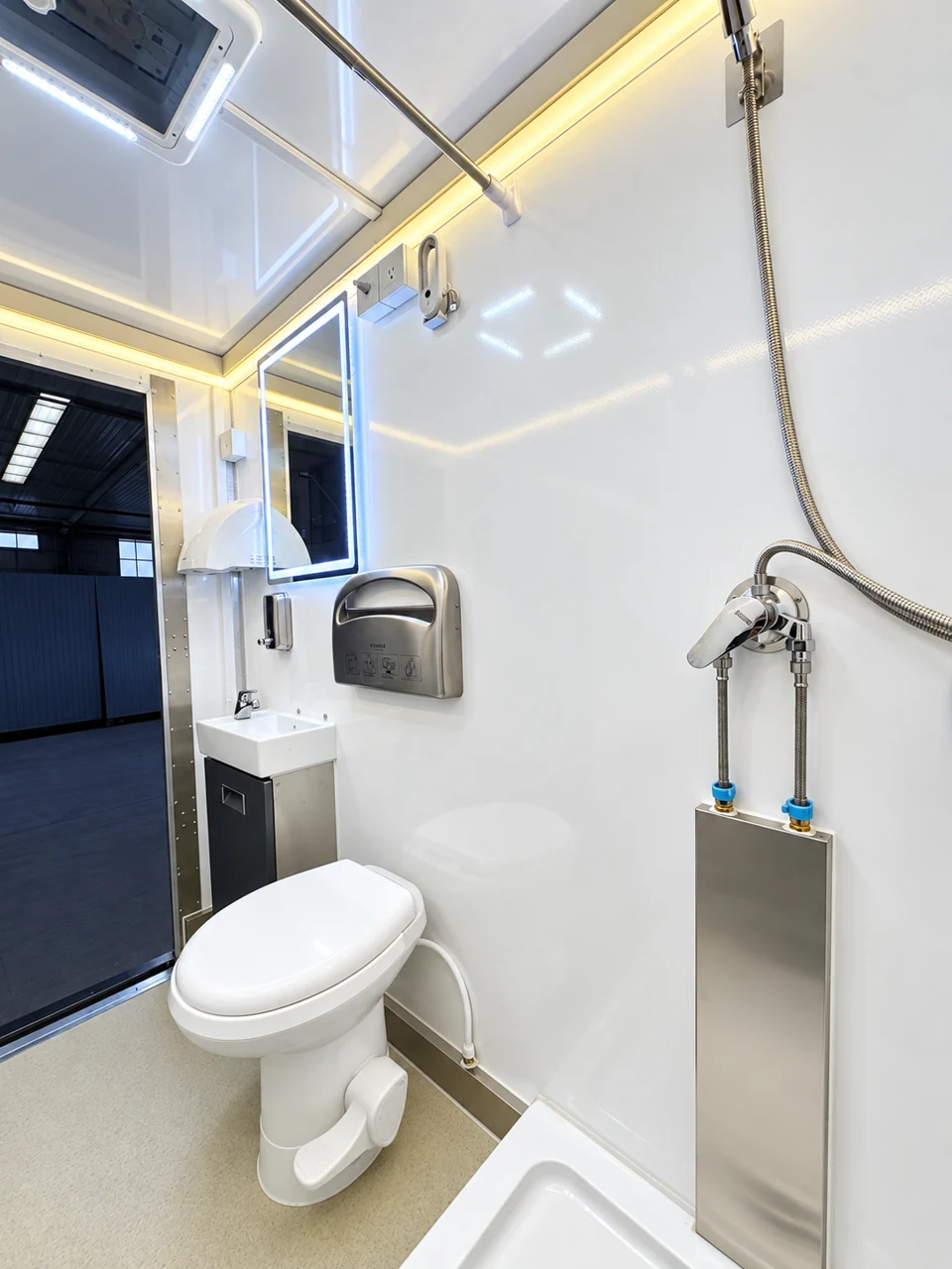 Toilet, sink and shower fixtures inside an accessible shower-restroom combination trailer